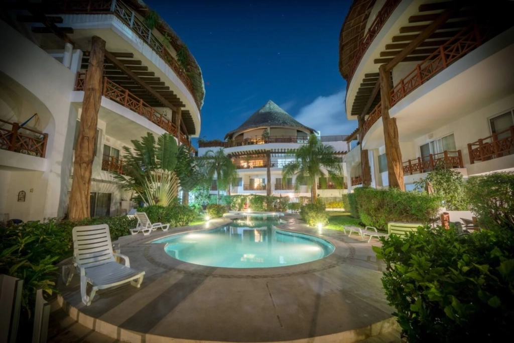 Profitez d’une piscine paisible au cœur d’une résidence tropicale à Playa del Carmen Piscine extérieure entourée de jardins tropicaux dans une résidence à Playa del Carmen