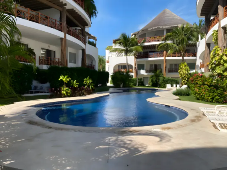 Une piscine privée au cœur d’un écrin verdoyant, idéale pour profiter pleinement de l’extérieur. Piscine extérieure aux formes arrondies entourée d’une villa et d’un jardin tropical.