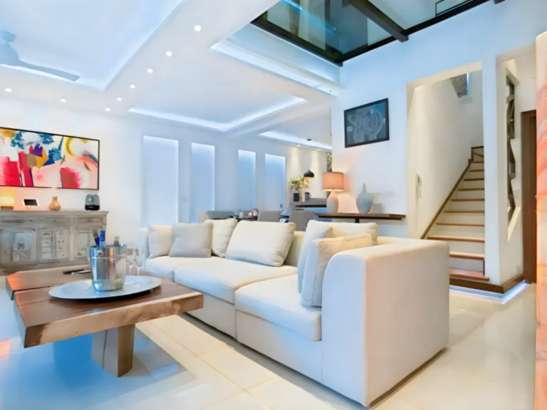 Un salon contemporain baigné de lumière, pensé dans une ambiance élégante et chaleureuse. Salon lumineux et élégant avec canapé blanc, mobilier contemporain et grandes ouvertures.